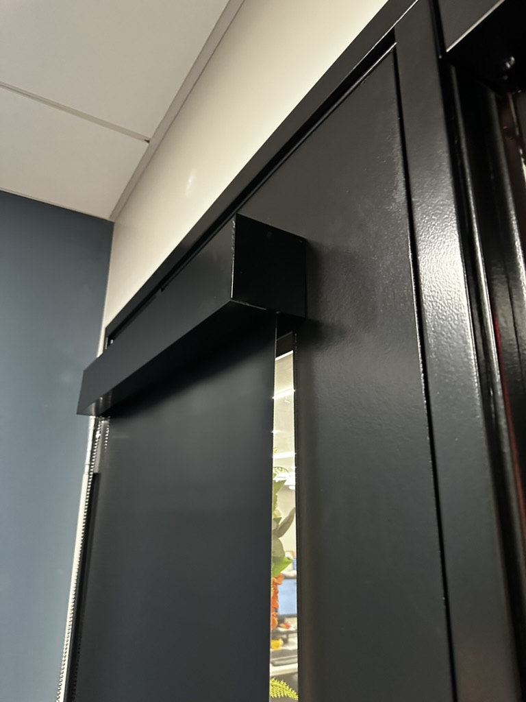 Close-up of black commercial sliding door track and hardware