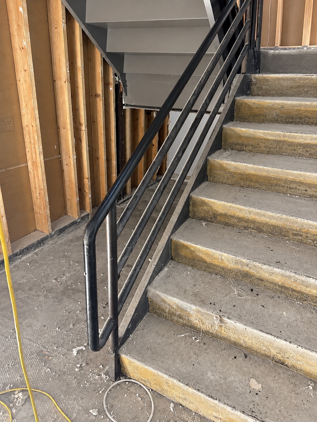 Black steel railing alongside concrete stairs in a commercial building under renovation