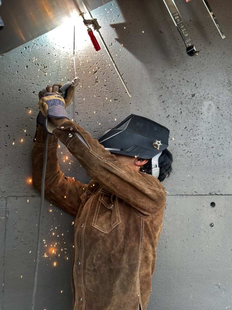Welder performing overhead industrial field work with sparks visible