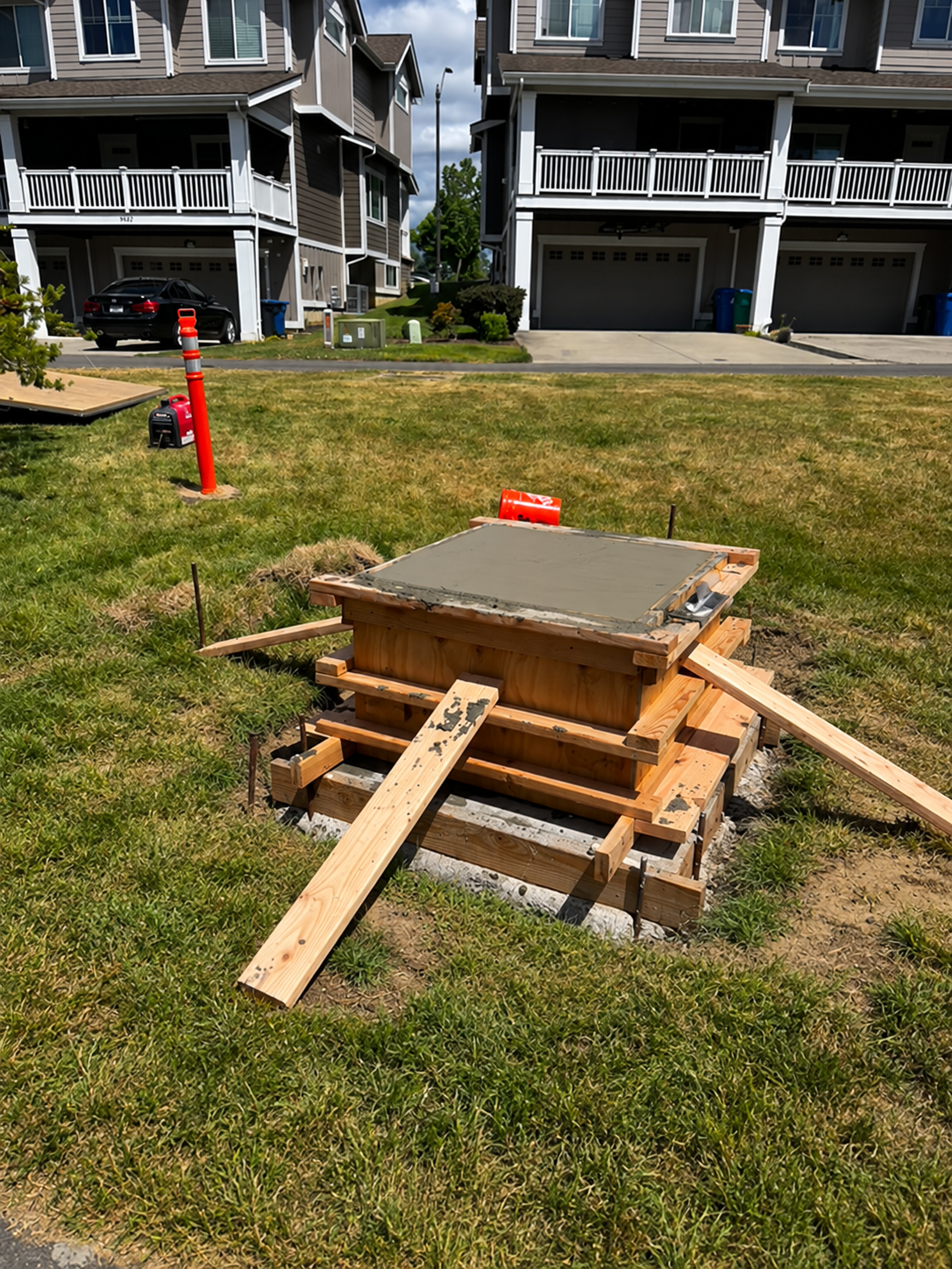 Fresh concrete cap and braced wood formwork for a public art pedestal
